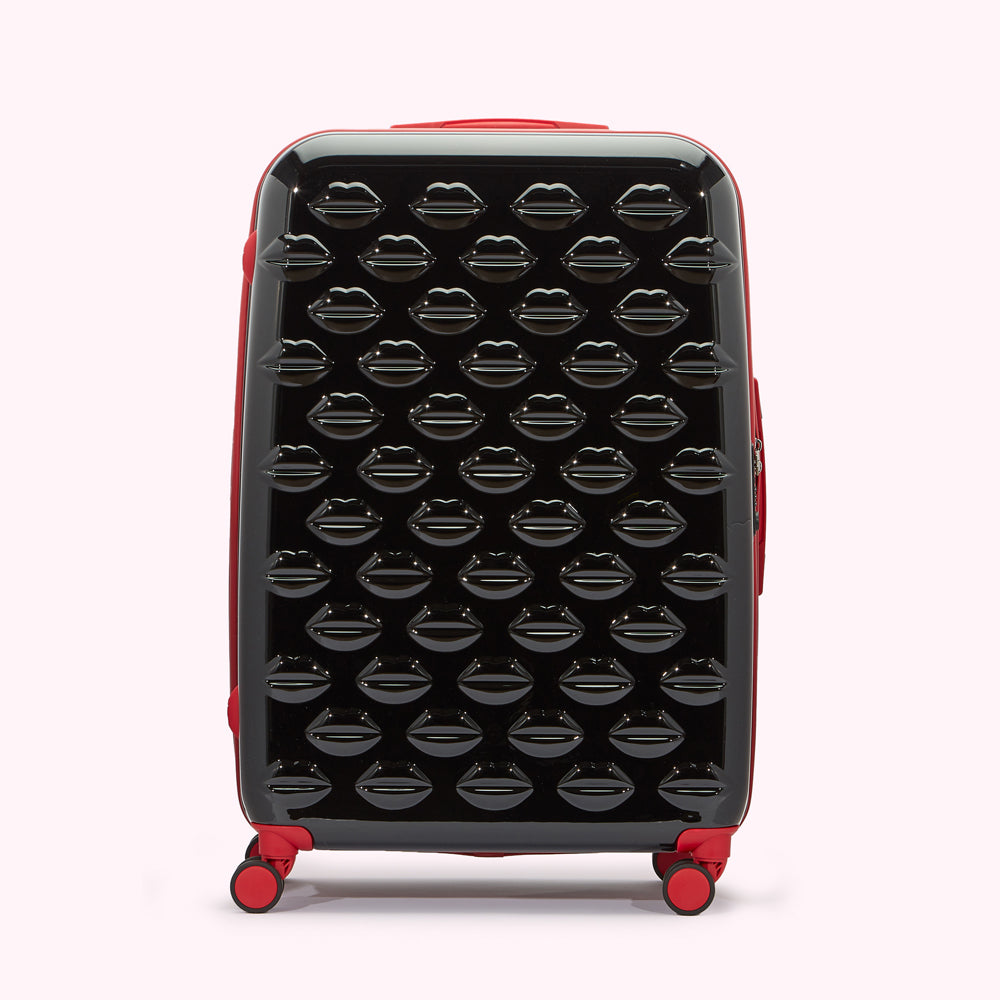 Black suitcase with red accents, covered in a pattern of embossed lips.
