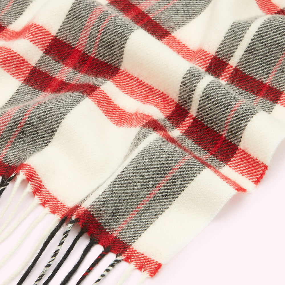 Close-up of a cream, red, and grey plaid or tartan scarf with fringe.
