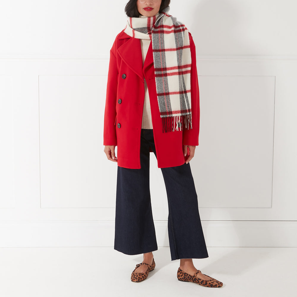 Woman in red coat, cream and red plaid or tartan scarf, dark blue wide-leg pants, and leopard print flats against a white background.
