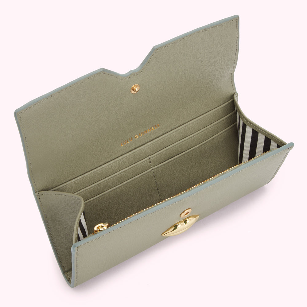 Sage green leather wallet open to reveal interior compartments and gold lip-shaped clasp.
