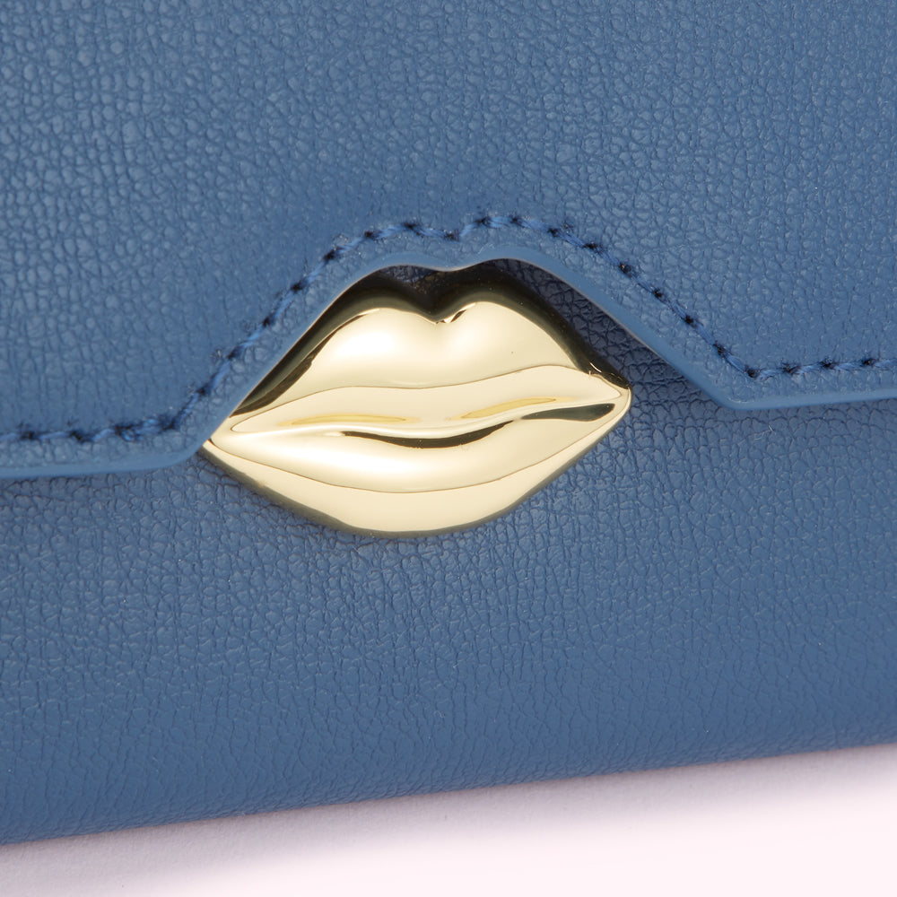 Close-up of a blue leather wallet with a gold lip-shaped clasp.
