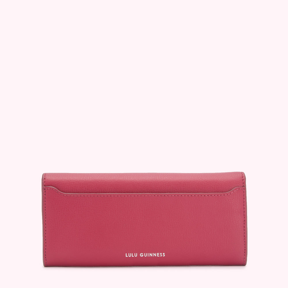 Pink Lulu Guinness wallet on white background.
