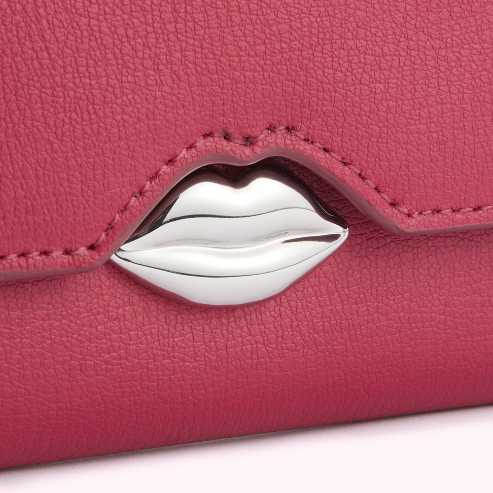 Close-up of a pink leather wallet with a silver lip-shaped clasp.
