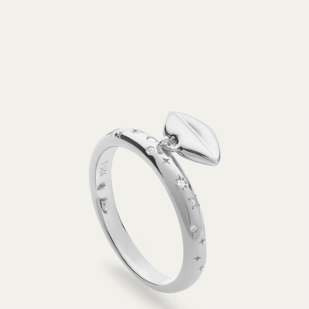 Silver ring with a lip-shaped pendant and inset stones on a off white background.