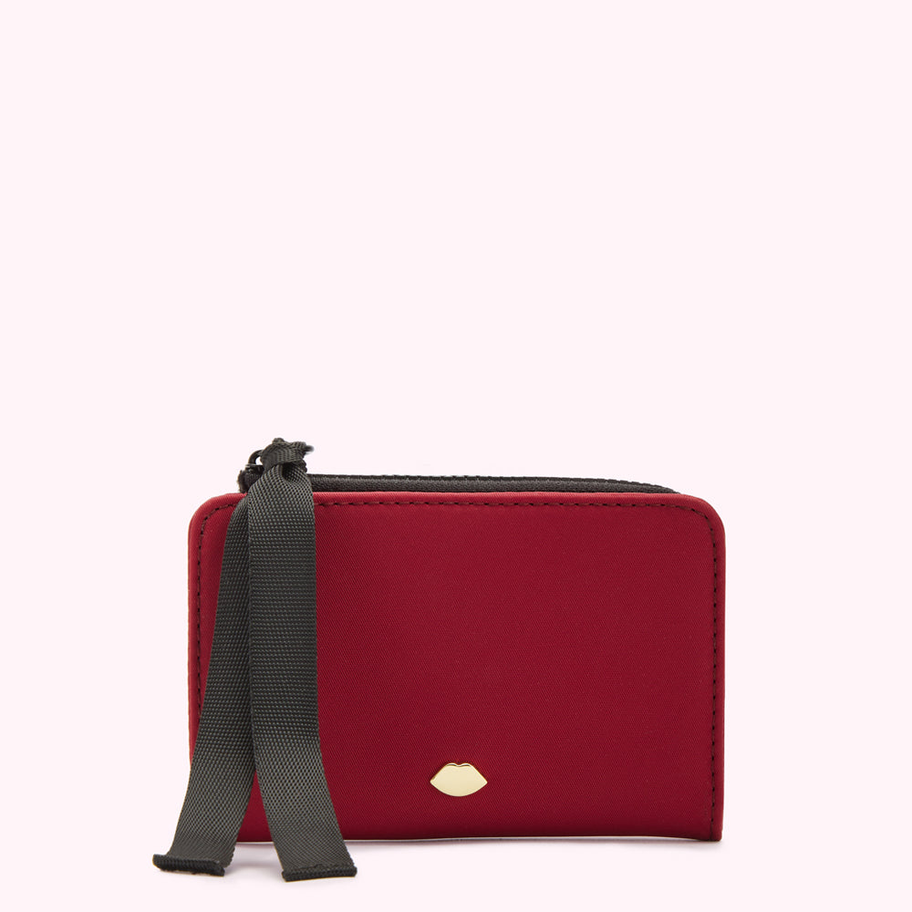 Red card holder with black ribbon and gold lip detail against a white background.
