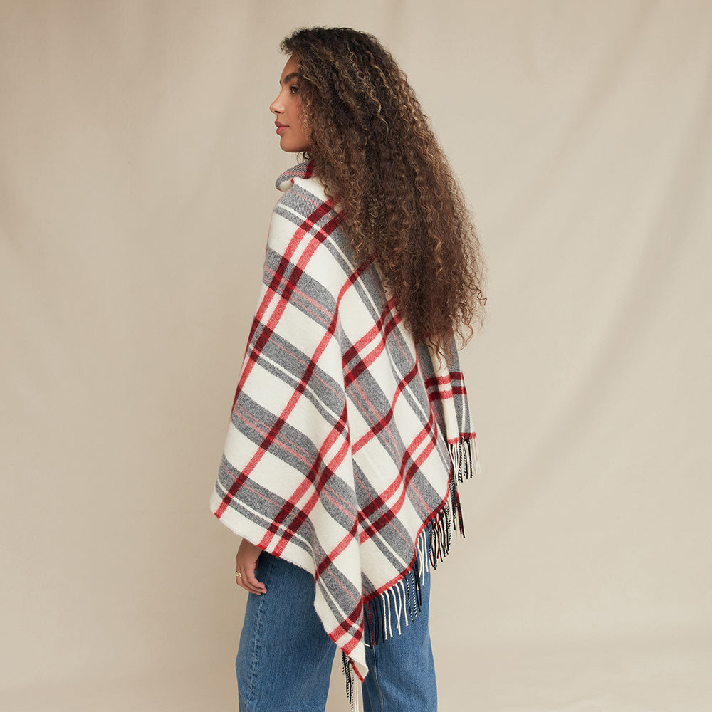 Woman wearing a plaid poncho against a beige background