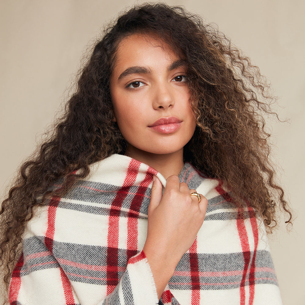 Woman wearing a plaid poncho against a neutral background