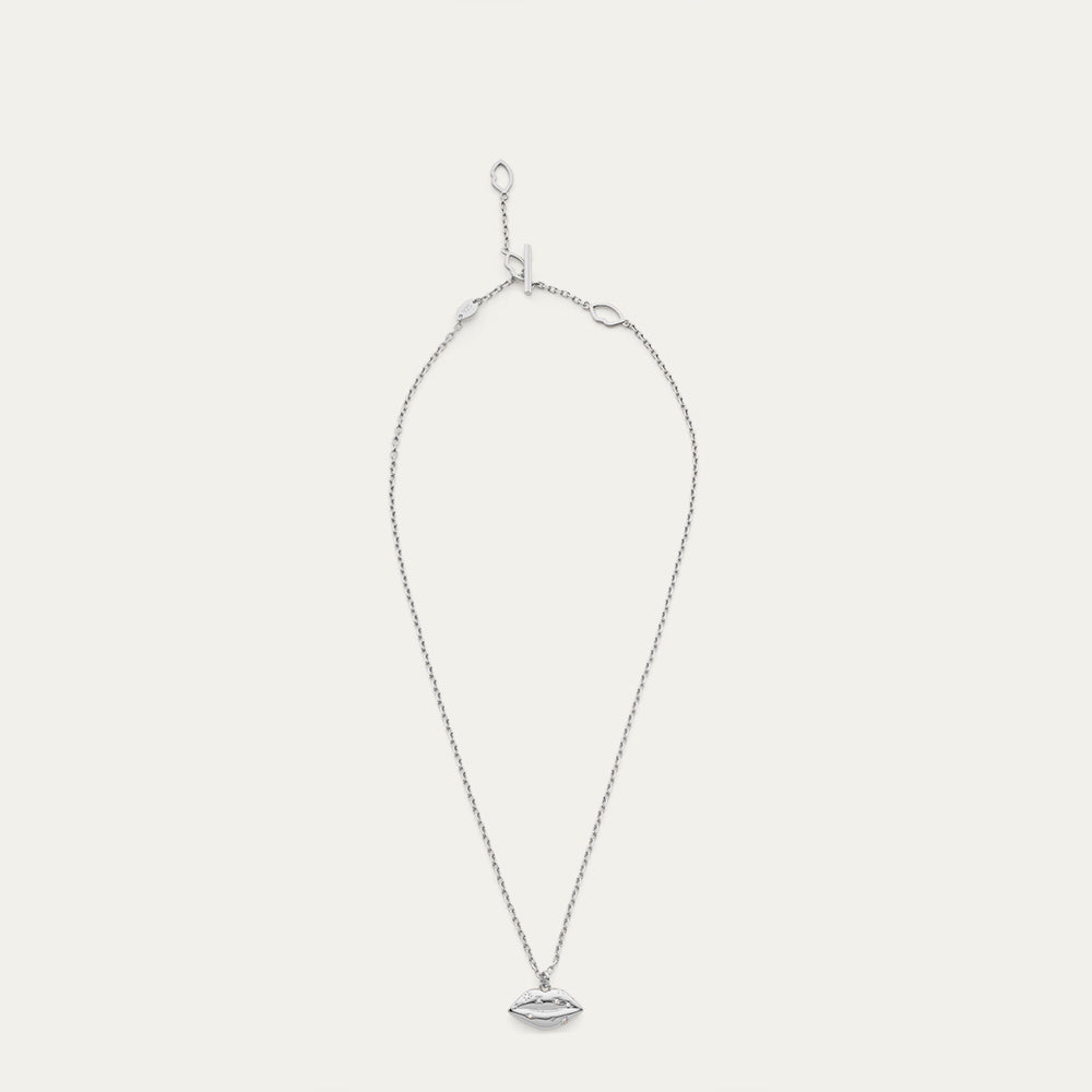 Silver necklace with a lip shaped pendant with a crystal design on a light gray background