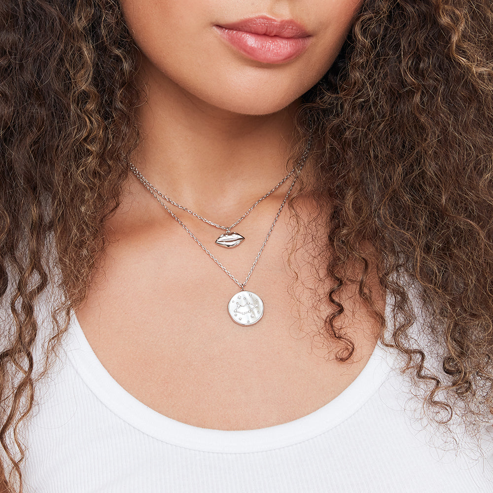 Close-up of a woman wearing two necklaces with pendants.