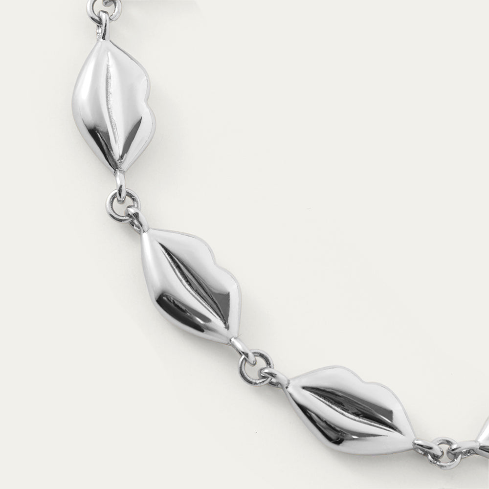 Silver bracelet with lip-like links on a white background