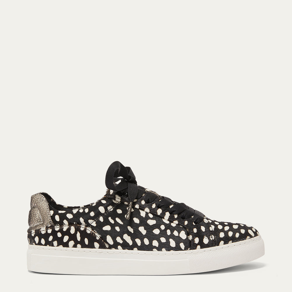 A black and white dot print trainer with a white sole and metallic details on the back.