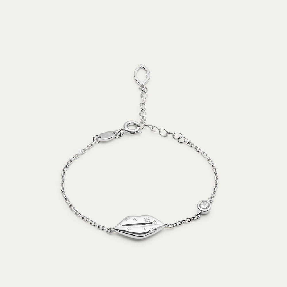 Silver bracelet with lip charm and inset crystals on a light gray background
