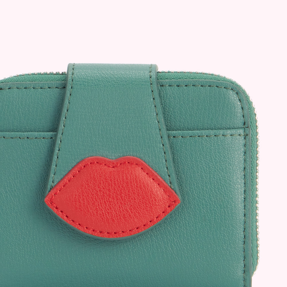 Close-up of a teal leather wallet with a red lips detail.
