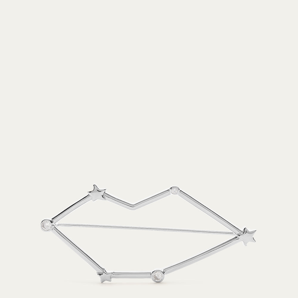 Silver lip shaped constellation brooch with star design on a light gray background