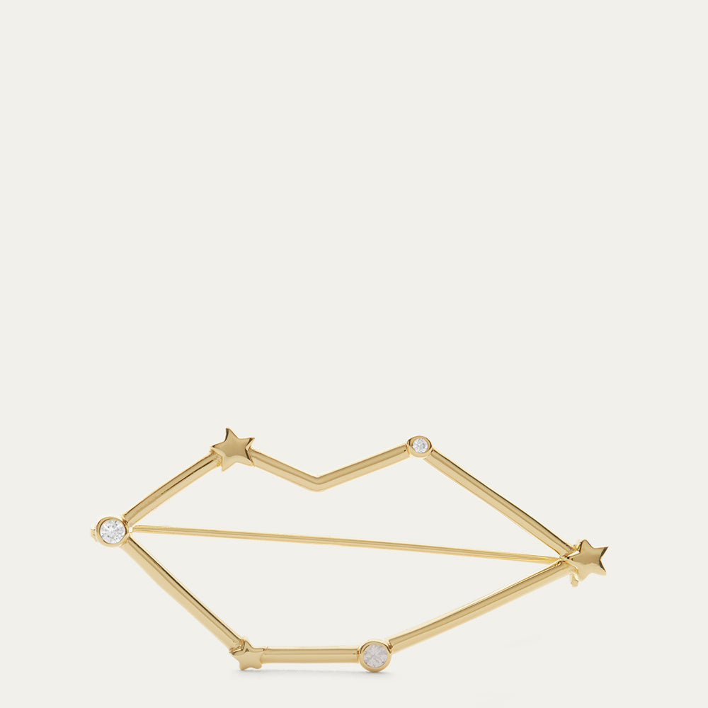 Gold lip shaped constellation brooch with star design on a white background