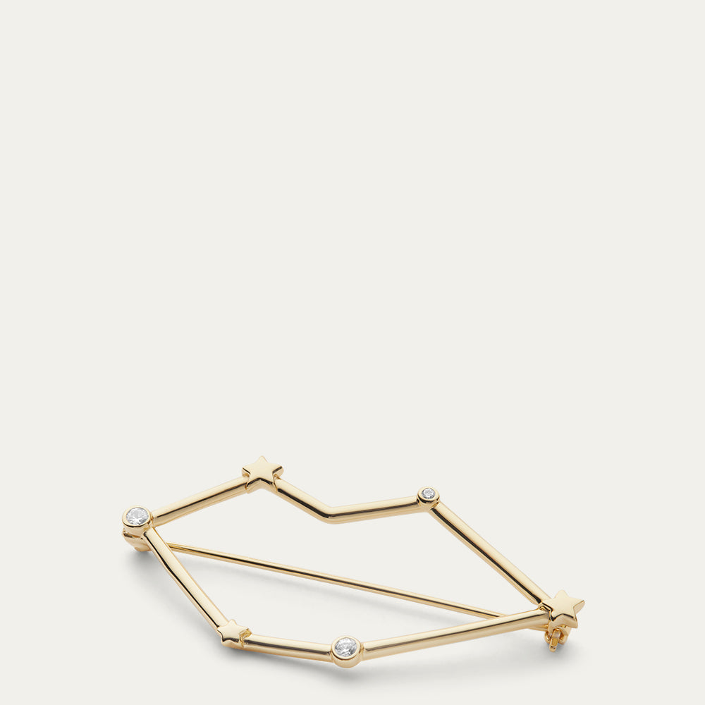 Gold lip shaped constellation brooch with star design on a white background