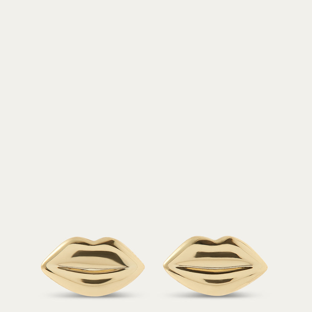 Gold lip-shaped earrings on a beige background