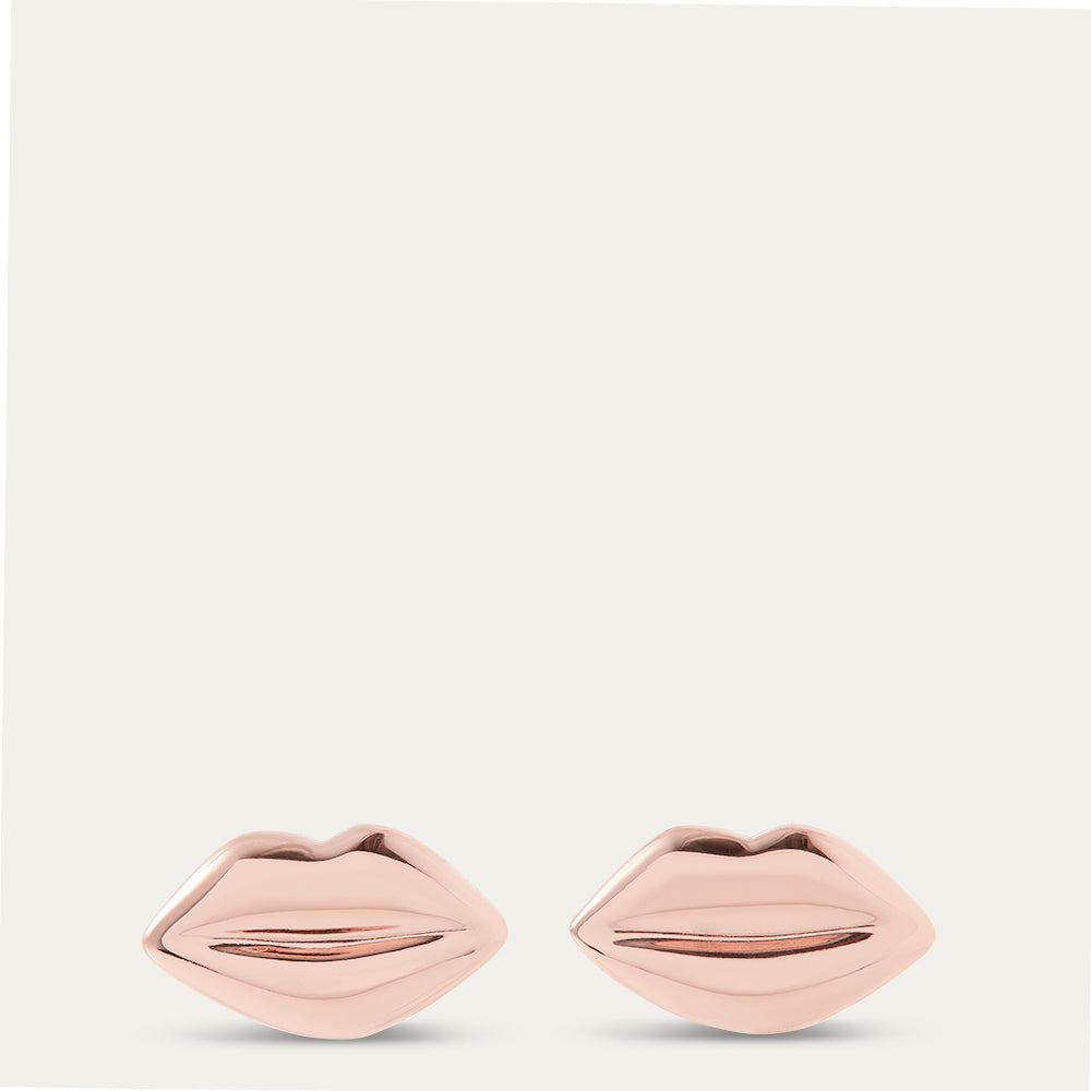 Lip-shaped earrings in rose gold on a light gray background
