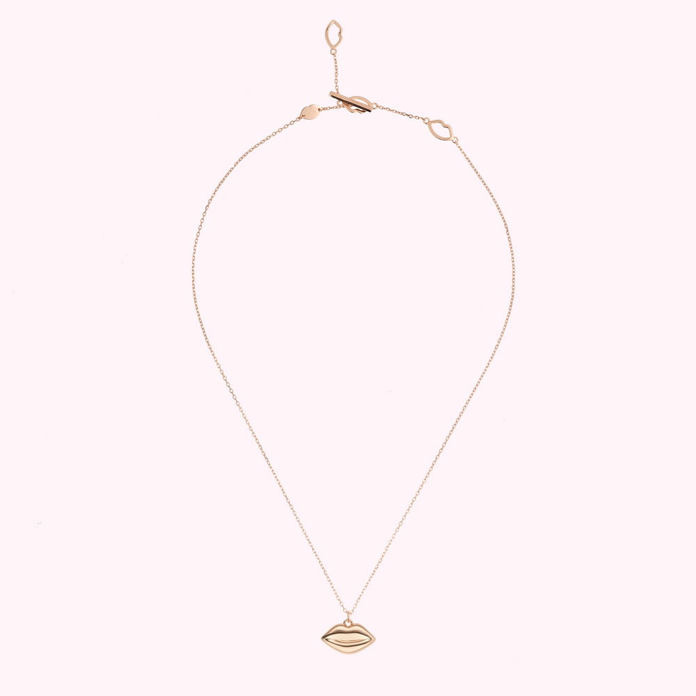 Rose gold necklace with lip pendant on white background.
