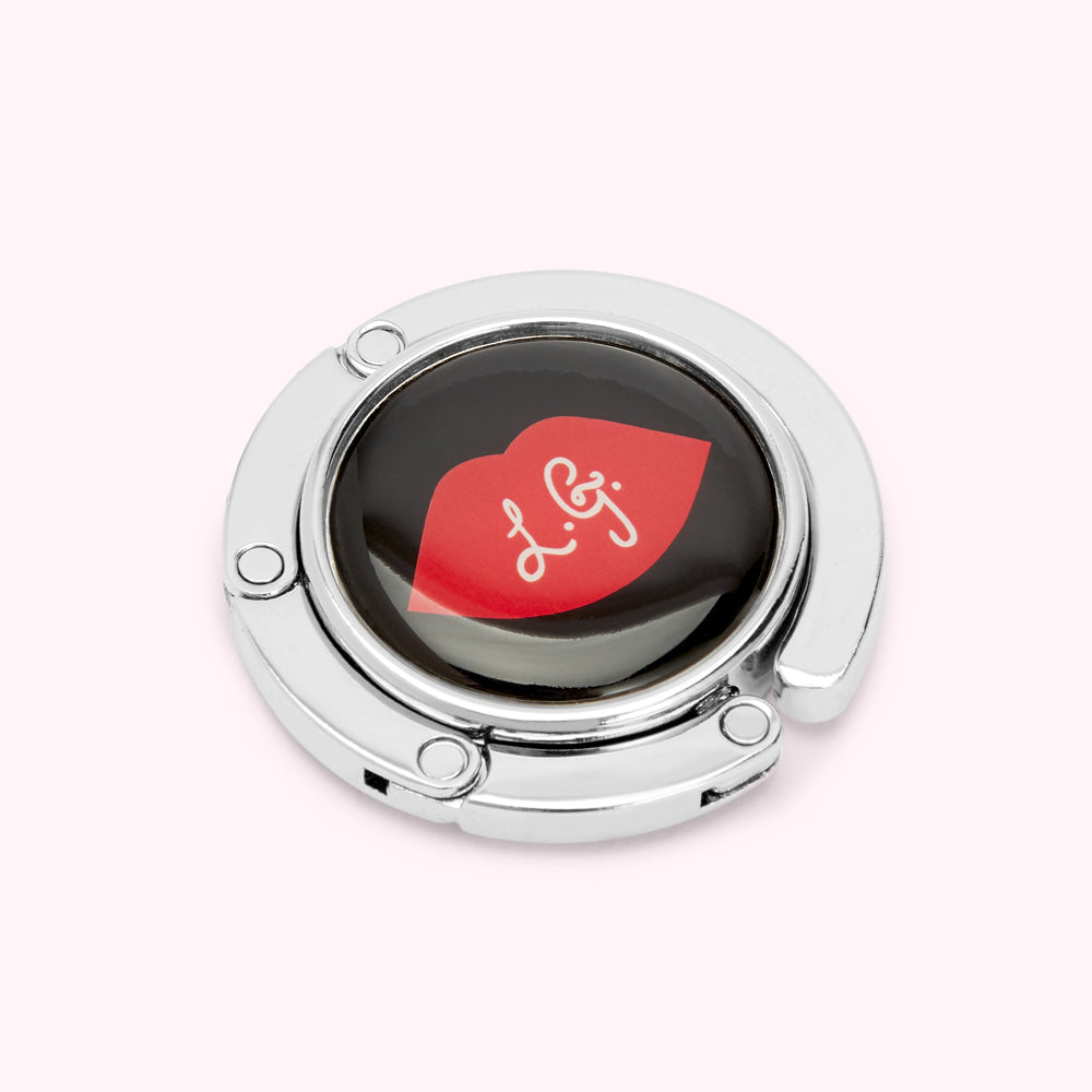 Silver handbag hook with a black and red lip design.