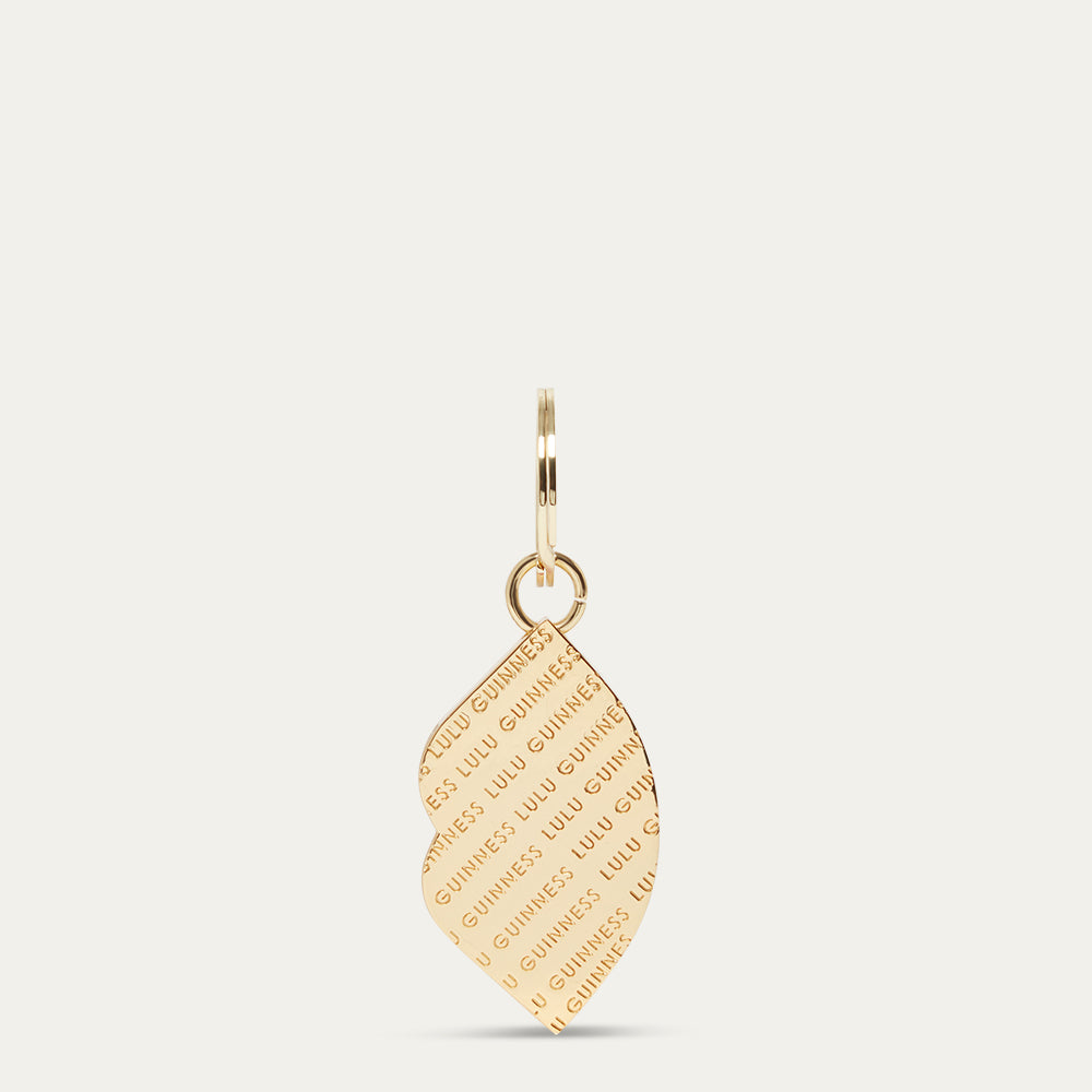 Gold lip shaped keyring with 'Lulu Guinness' engraved branding on a white background