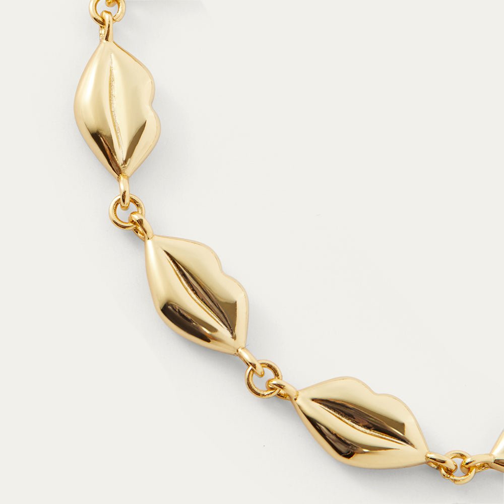Gold bracelet with lip-shaped links on a light gray background