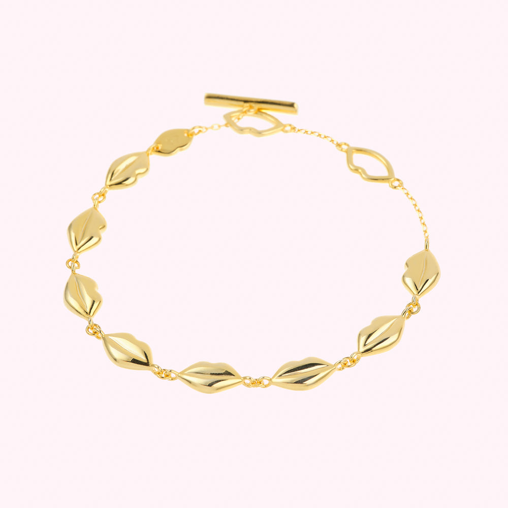 Gold bracelet with lip-shaped charms on a delicate chain.