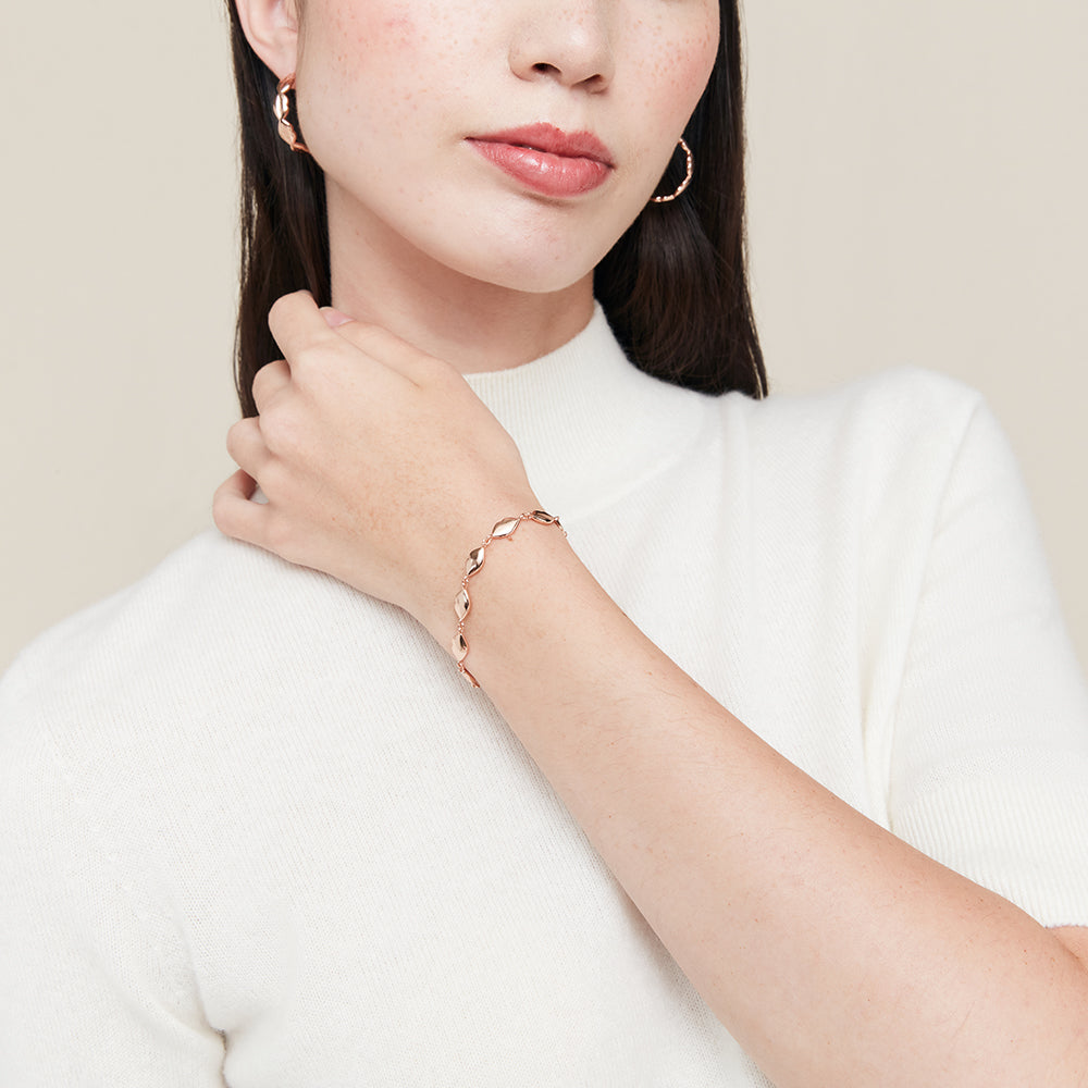 Woman wearing a rose gold bracelet on a plain background