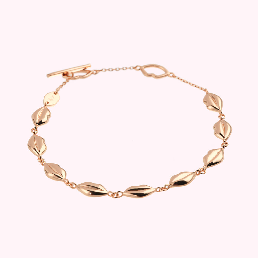 Rose gold bracelet with lip-shaped charms and a heart-shaped clasp.
