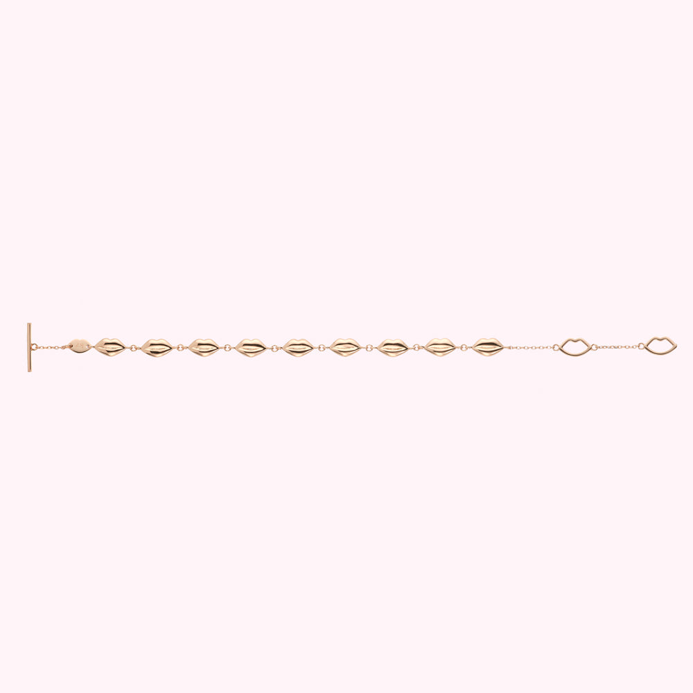 Gold lip-shaped bracelet on white background.
