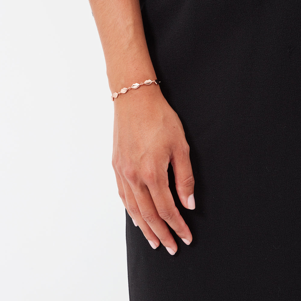 Rose gold shell bracelet on a wrist against a white background.