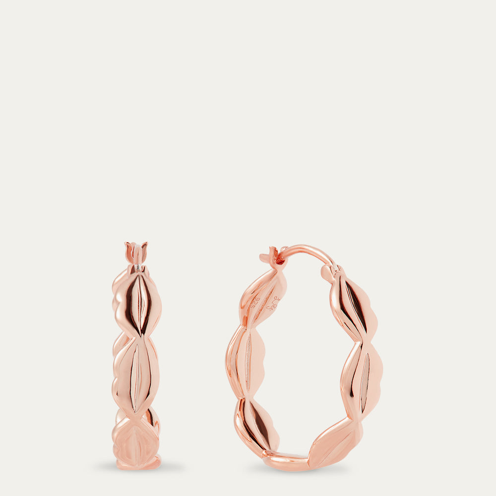 Rose gold hoop earrings on a light beige background