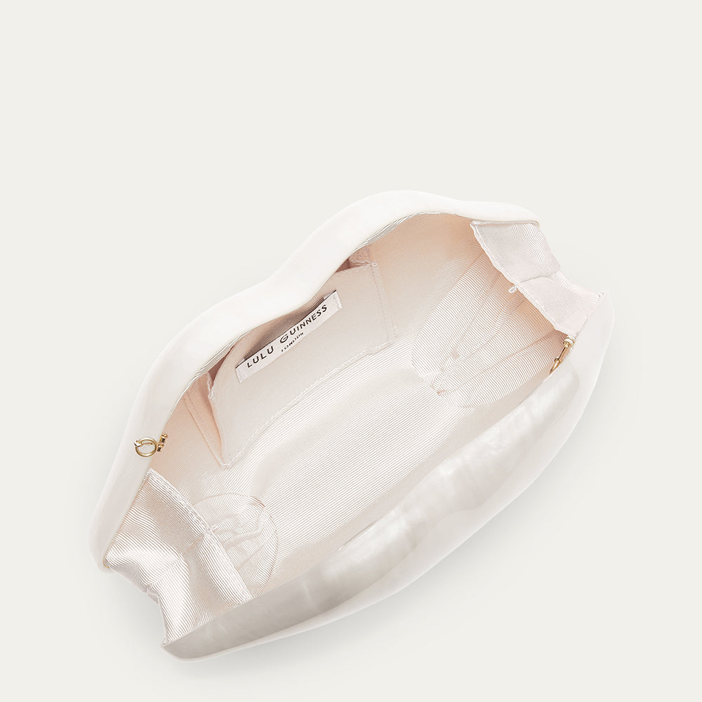 White lip shaped clutch open to reveal a ivory lining on a white background