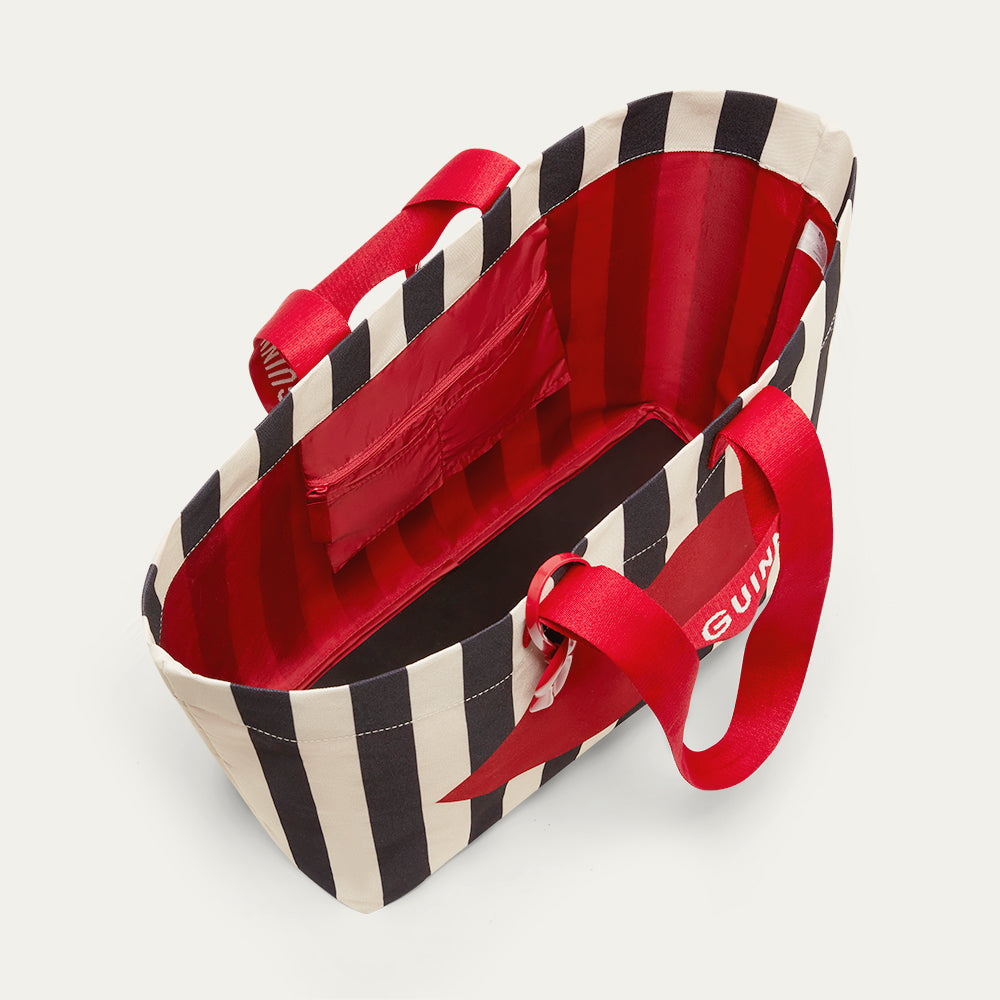 Inside image of a striped black and beige tote bag with red handles, showing the inside pocket on a light grey background