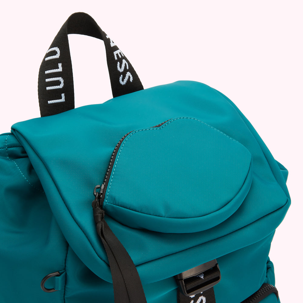 Close-up of a teal Lulu Guinness backpack with a lip-shaped zipper pocket.
