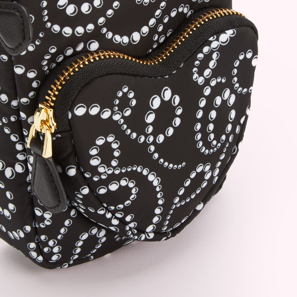 Close-up of a black heart-shaped bag with a white pearl pattern and gold zipper.

