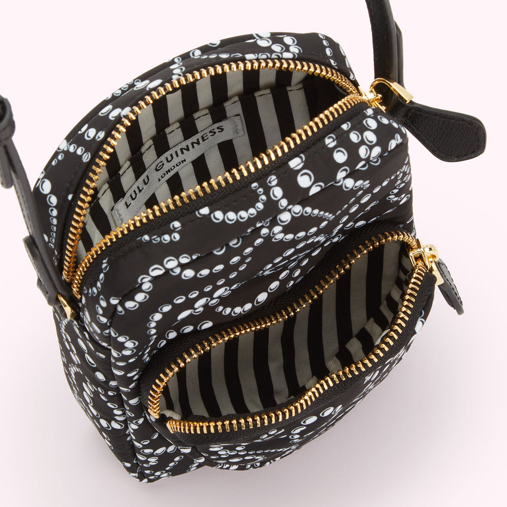 Black Lulu Guinness crossbody bag with white pearl pattern, gold zippers, and black and white striped interior.
