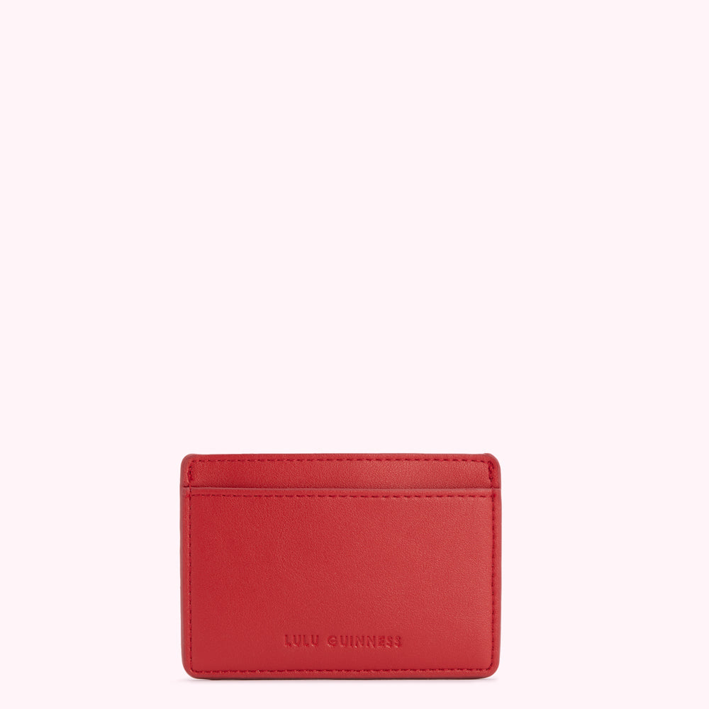 Red leather Lulu Guinness cardholder against a white background.
