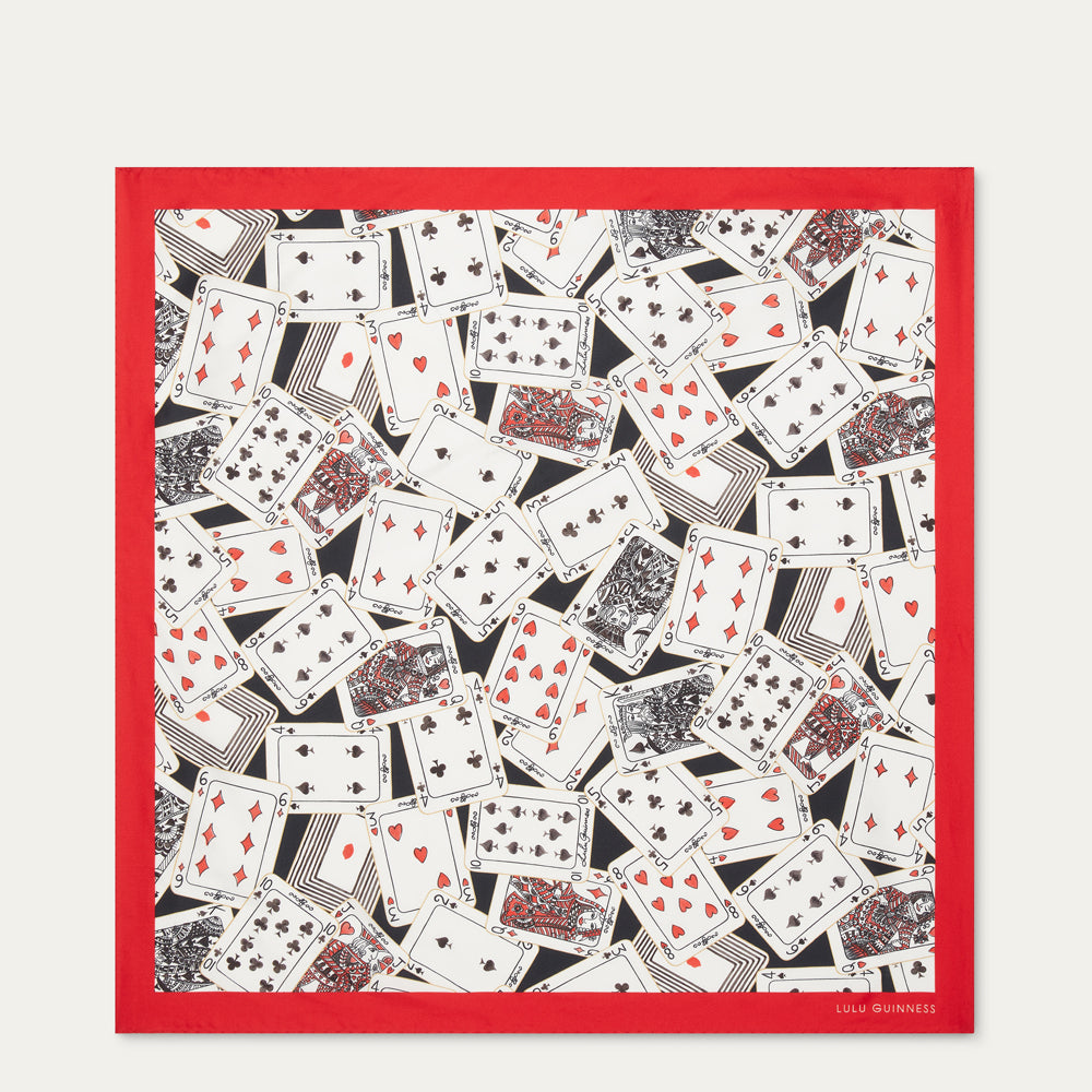 A square art print silk scarf featuring an all-over pattern of overlapping playing cards in black, white, and red, framed by a solid red border on a light gray background.