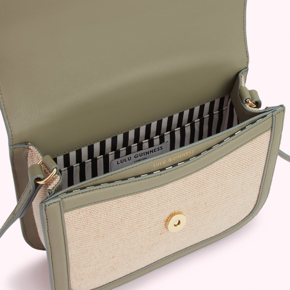 Open sage green Lulu Guinness crossbody bag with beige canvas front panel and black and white striped interior.
