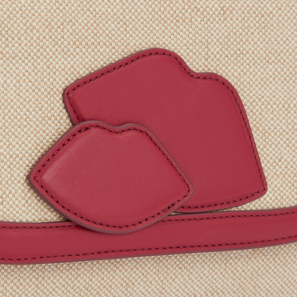 Close-up of a beige canvas bag with red leather lip-shaped appliqué.