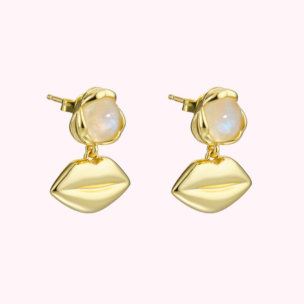 Gold earrings with moonstone accents and lip-shaped charms.

