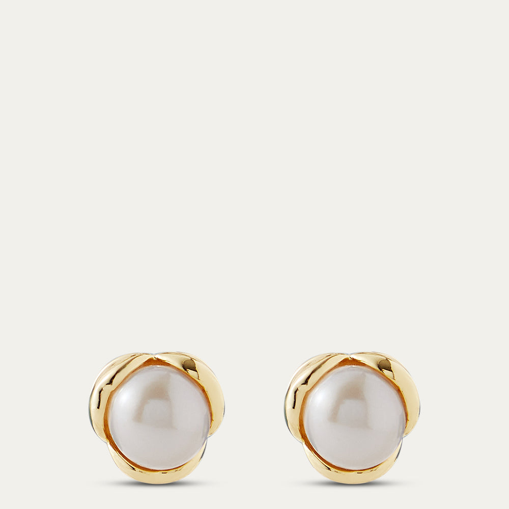 Pair of pearl earrings with gold rims on a light beige background