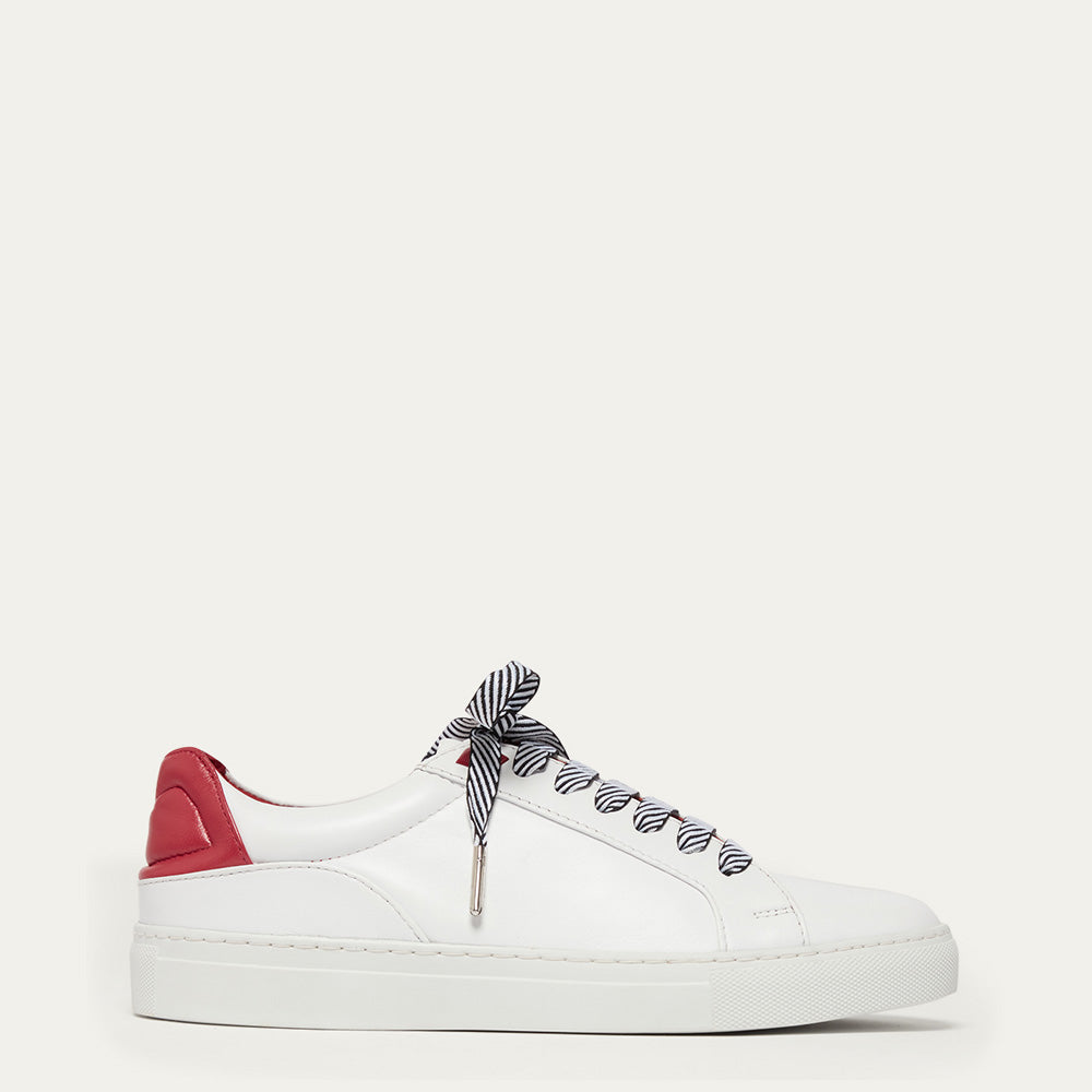 White sneaker with red heel and black and white striped laces on a white background