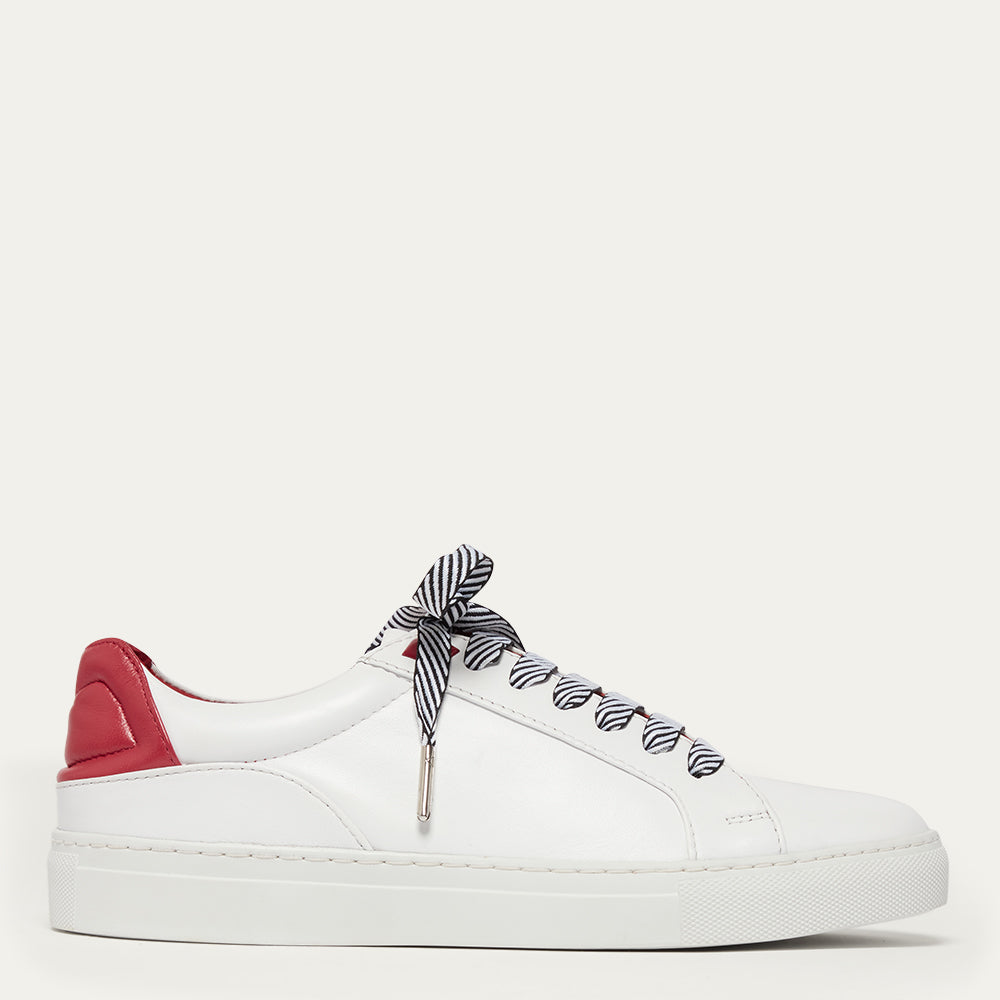 White sneaker with red heel and black and white striped laces on a white background