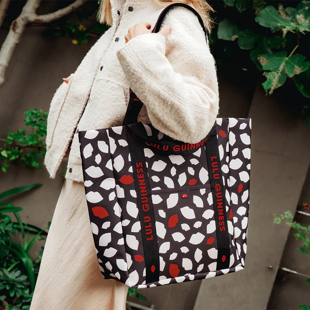 Person holding a Lulu Guinness bag with a lip flurry print of red, white and black