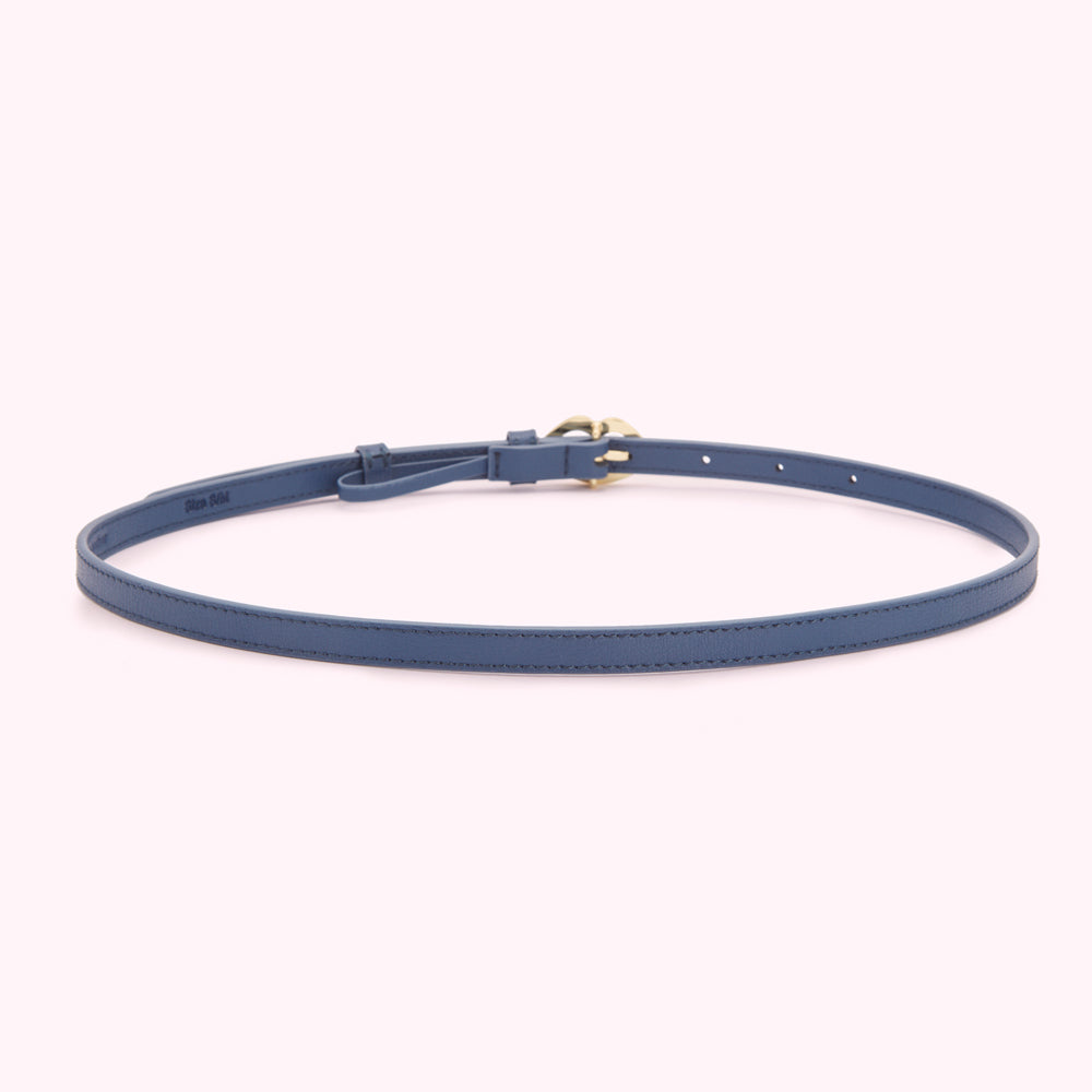 A dark blue leather belt with a gold buckle on a light pink background.
