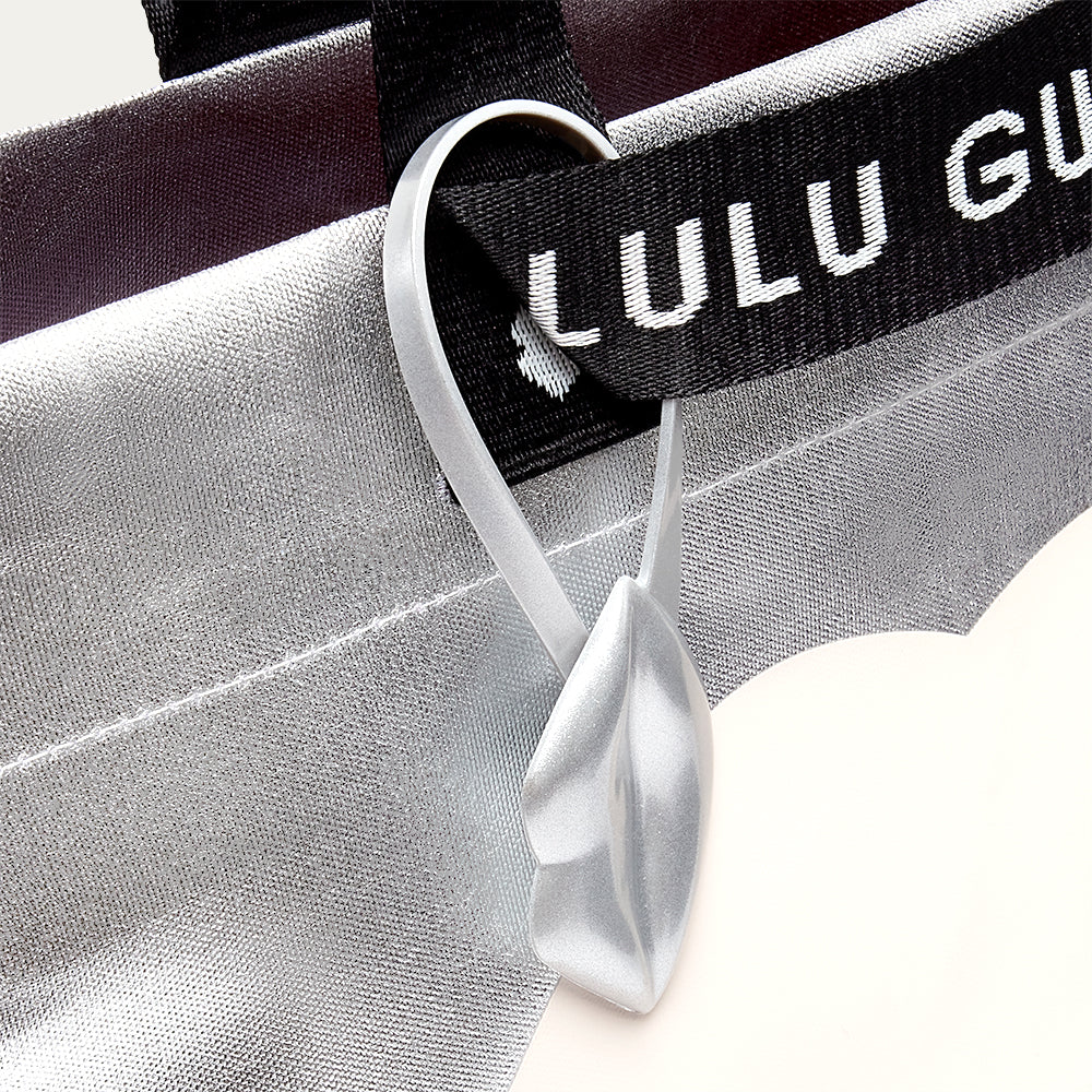 Close-up of a Lulu Guinness tote bag with a lip tag charm on a white background