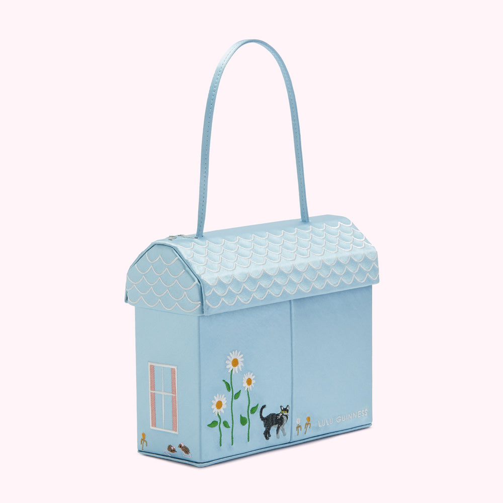 Light blue house-shaped handbag with embroidered details including flowers, a cat, and the Lulu Guinness logo.