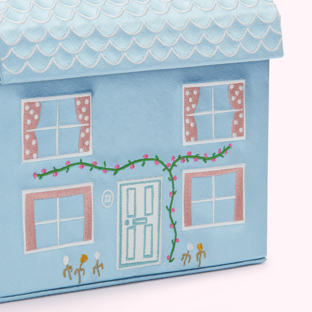 Light blue house-shaped storage box with embroidered details, including windows, a door, flowers, and a vine.